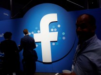 FILE PHOTO: Attendees walk past a Facebook logo during Facebook Inc's F8 developers conference in San Jose