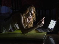 Young woman using laptop and cell phone late at night model released Symbolfoto PUBLICATIONxINxGERxSUIxAUTxHUNxONLY AFV