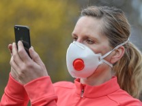 Coronavirus - Frau mit Atemschutzmaske und Handy